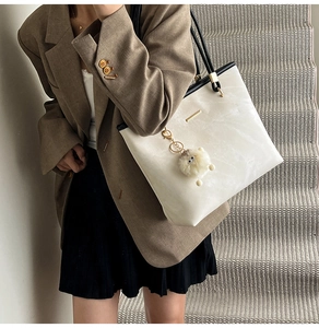 Detail of high-capacity tote bag with marble pattern leather and stylish plush pendant