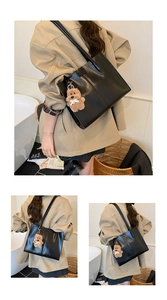 Detail view of black vintage tote bag with high-gloss finish and plush bear pendant
