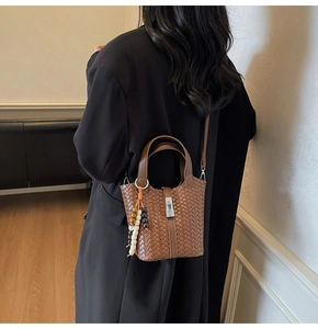 Détail du sac seau en cuir tressé avec breloque en perles de bois et fermoir en métal