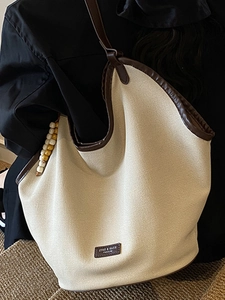 Chic beige canvas underarm hobo bag with brown trim and beaded pendant detail