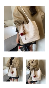 Detailed view of woven texture tote bag with brown sphere charm and double shoulder straps
