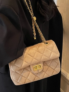 Borsa a tracolla trapuntata beige con catena dorata e motivo a rombi su un abito nero