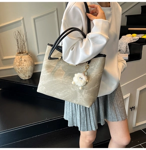 Detail view of stylish marble texture tote bag with a cute white plush eye keychain