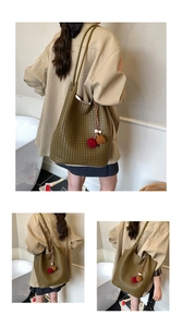 Detail view of large olive green woven tote bag with bicolor pompom and spacious interior