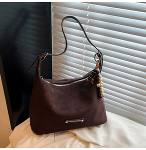 Detail view of brown suede tote bag with leather strap and vintage wooden bead charm