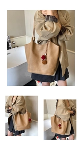 Detail view of woven texture on khaki tote bag with colorful plush ball charm