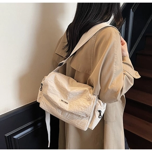 Detail of white nylon tote bag with pleated texture and adjustable strap on a model