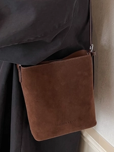 Minimalist dark brown suede tote bucket bag with elegant shoulder strap and embossed lettering