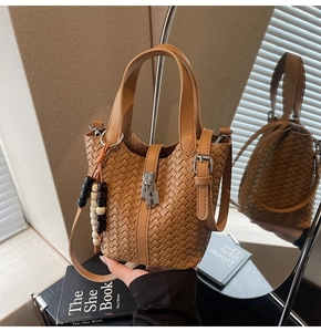 Détail du sac seau marron tressé avec serrure argentée et pompon à perles décoratif