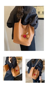 Close-up of woven brown tote bag with matching zippered pouch and colorful pom pom charm