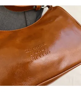 Detail of caramel oil wax leather texture and embossed logo on the vintage baguette bag