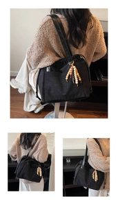 Detail of black tote bag with drawstring closure and decorative wooden bead tassel charm