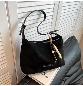 Detail of black suede hobo bag with adjustable strap and decorative wooden bead charms