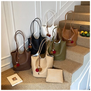 Close-up of woven tote bags in various colors featuring contrast pompoms and matching pouches