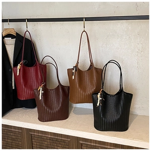 Detail view of woven leather tote bags in burgundy, brown, tan and black with bead tassels