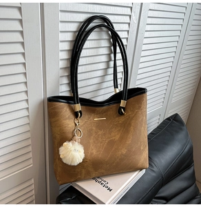 Detail of tan suede tote bag with gold metal trim and white plush sheep keychain