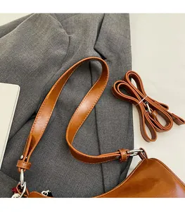 Detailed macro view of the glossy brown leather shoulder strap with a silver metal buckle