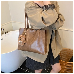 Detail of vintage brown tote bag with smooth texture and cute puppy plush pendant
