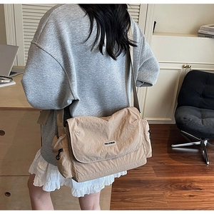 Close-up of beige nylon messenger bag with adjustable strap and side zipper detail