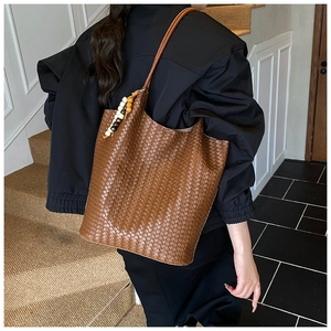 Detail of woven brown leather tote bag with colorful wooden beads on the shoulder strap