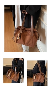 Detail of brown suede drawstring tote bag with vintage beaded charm and leather handles