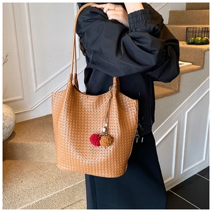 Close-up of brown woven texture on large bucket bag with red pom pom tassel detail
