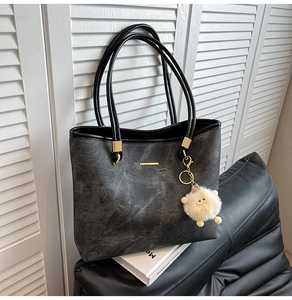 Detail showing marble-textured large tote bag with metallic bar and cute sheep pendant