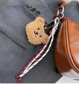 Detail of plush bear charm with woven tassels on a brown leather handbag accessory