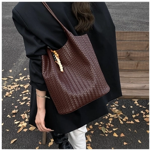 Detail of dark brown woven tote bag with wooden beads in a cozy autumn street setting