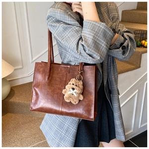 Detailed view of brown vintage tote bag with oil-wax texture and cute bear charm