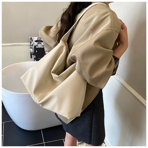 Detailed side view of cream faux leather tote bag with soft lychee grain texture