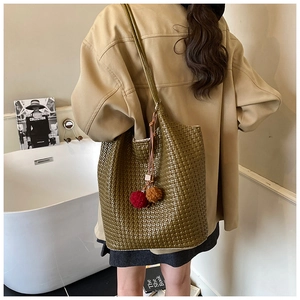 Close-up of olive green woven texture tote bag with colorful plush ball tassel detail