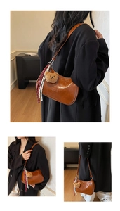 Detail of vintage brown shoulder bag with plush bear charm and woven rope decoration