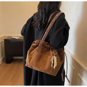 Detail view of caramel brown suede tote bag with drawstring closure and vintage wood beads