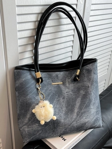 Large gray washed tote bag with black straps and cute monster plush charm on side