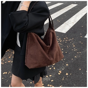Street style view of large brown suede tote bag featuring a minimalist triangular structure