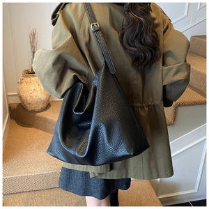Detail of black pebbled leather texture on large hobo bag with adjustable shoulder strap