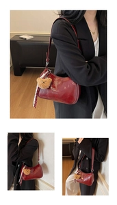 Detail of dark red vintage underarm bag with Classic embossing and bear charm accessory