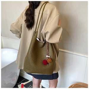 Detail showing woven texture of olive green tote bag with decorative plush charms