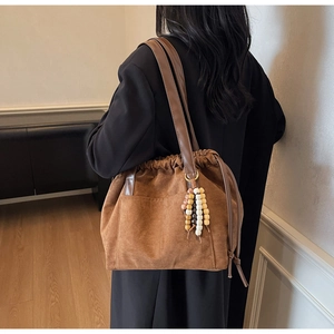 Detail of brown suede tote bag with drawstring closure and decorative wooden beads