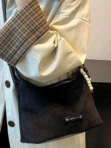 Minimalist black suede tote bag with stylish wooden bead pendant and metal logo detail