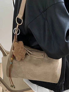 Khaki suede tote bag with teddy bear charm and colorful beads on leather jacket