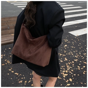 Outdoor street shot of large brown suede tote bag carried by a model in a black blazer