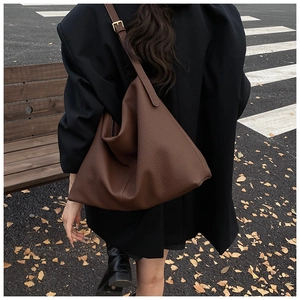 Detail of a large dark brown hobo bag with litchi texture on a street background