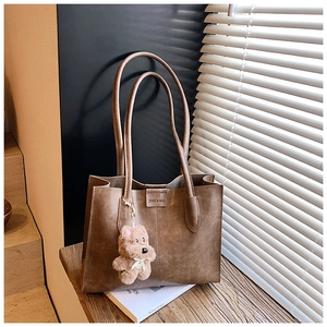 Detail of vintage brown tote bag texture with brand logo and plush bear charm