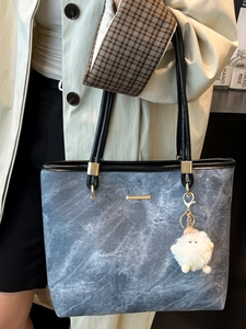 Blue marble textured large tote bag with black handles and white fuzzy charm detail