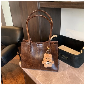 Detail view of vintage dark brown faux leather tote bag with stylish bear pendant accessory