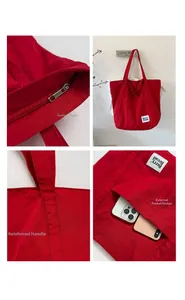 Detail view of red canvas tote bag showing metal zipper and external pocket design