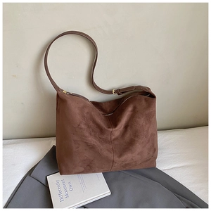 Detailed close-up of brown suede shoulder bag featuring a gold zipper and adjustable strap