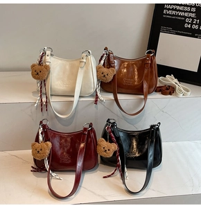 Detailed view of four glossy vintage-style shoulder bags in diverse fall colors with charms